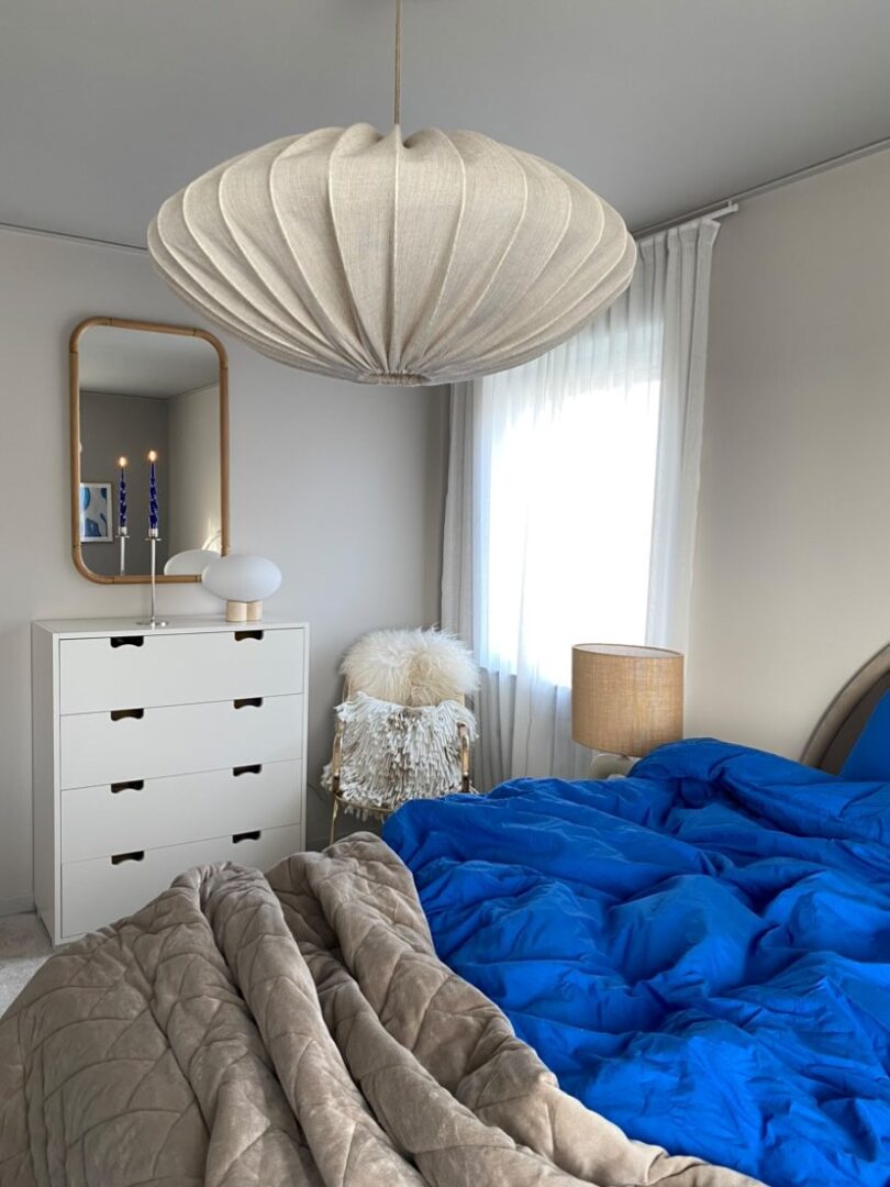 Spegel med träram upphängd i sovrum med blåa lakan