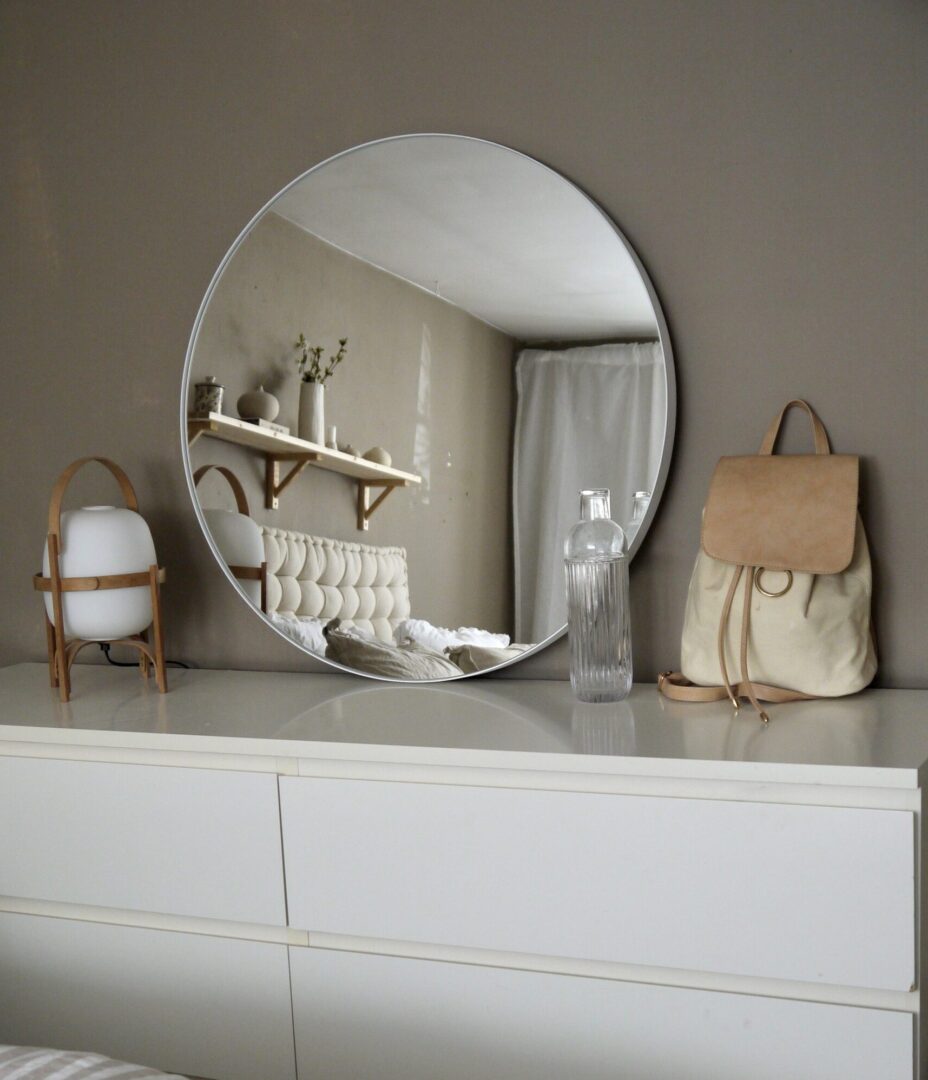 Rund spegel med vit metallram i sovrum